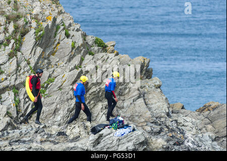 Urlauber und ein Ausbilder Vorbereitung einer coasteering Session auf der Landspitze in Newquay, Cornwall zu starten. Stockfoto