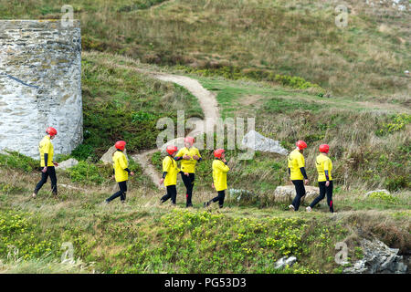Eine Gruppe von Urlaubern Hören zu einem Ausbilder eine Sicherheit sprechen, bevor Sie ein coasteering Session auf der Landspitze in Newquay, Cornwall beginnen. Stockfoto