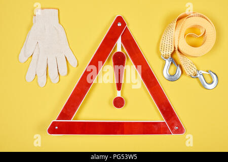 Draufsicht auf das Warndreieck Schild, Handschuhe und Car Schleppseil isoliert auf Gelb Stockfoto