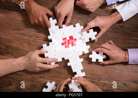 Erhöhten Blick auf Geschäftsleute Lösung Puzzle über Holz- Hintergrund Stockfoto