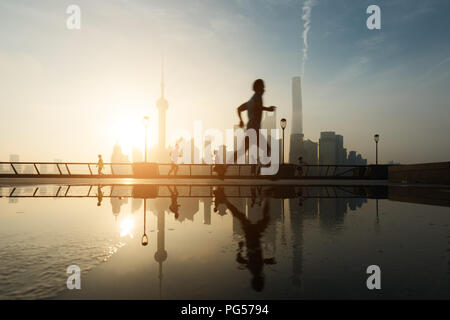 Menschen, die morgens am Huangpu-Fluss am Flussufer mit Shanghai downtown im Hintergrund laufen, in Shanghai, China. Stockfoto