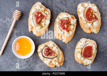 Snacks Bruschetta mit Frischkäse, Walnuss und Honig und Feigen auf einem dunklen Hintergrund. Stockfoto