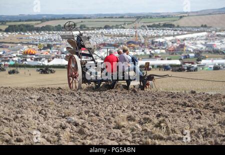 Enthusiasten mit einem Pflug, Winched durch zwei Dampfmaschinen, im Feld pflügen am Great Dorset Steam Fair, Tarrant Hinton, in der Nähe von Blandford Forum, wo Hunderte von dampfbetriebene Zugmaschinen und schwere mechanische Ausrüstung aus allen Epochen, für die jährliche zeigen, welche bis zum Feiertag Montag und feiert dieses Jahr sein 50-jähriges Jubiläum läuft sammeln. Stockfoto