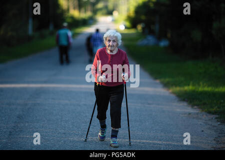 Eine ältere Frau im Nordic aktiv Walking mit Stöcken. Stockfoto