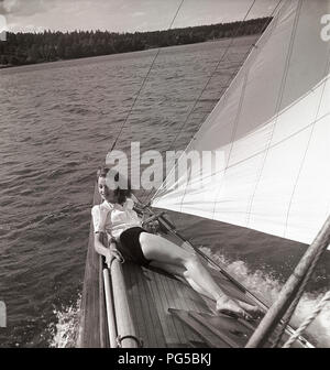 1940 s Segelboot. Eine junge Frau ist an Bord eine modische Segelboot und liegt auf Deck, wenn es vorwärts Kreuzfahrten mit Wind in den Segeln. Sie trägt eine typische 40er Jahre Mode. Schweden 1946 Foto Kristoffersson ref AC 102-5 Stockfoto