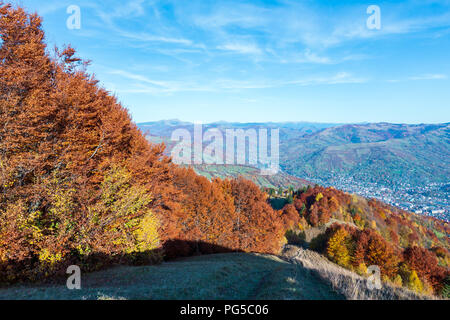 Herbst Karpaten Landschaft mit bunten gelb-orange-rot-braun Bäume am Hang und Rakhiv Stadt in weit unter (Ansicht von rakhiv Pass, T Stockfoto