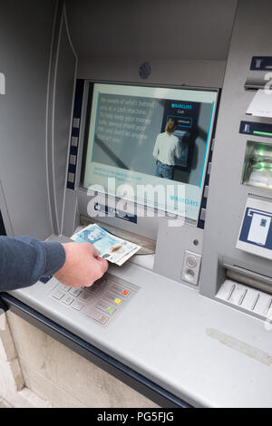 Eine Frau entfernt und 5 £ £ 10 Notizen von einem außerhalb der Barclays Bank, Loch in der Wand, Cash point maschine Stockfoto