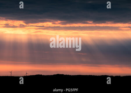 Eine einsame Windturbine auf einem Hügel bei Sonnenuntergang in der Nähe von Uddevalla, an der Westküste von Schweden. Sonnenstrahlen (besser bekannt als Sonnenstrahlen bekannt) Stockfoto