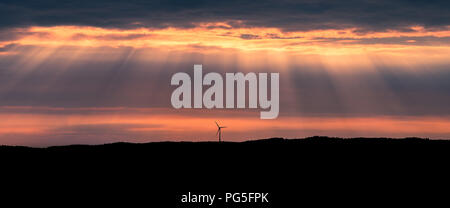 Eine einsame Windturbine auf einem Hügel bei Sonnenuntergang in der Nähe von Uddevalla, an der Westküste von Schweden. Sonnenstrahlen (besser bekannt als Sonnenstrahlen bekannt) Stockfoto