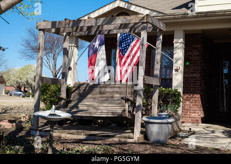 Texas Flag & amerikanische Flagge auf erweiterten Fahnenmasten außerhalb in McKinney Texas. Alte hölzerne Schwingen, Stern von Texas mit Pferd Schuhe auf Haus Säulen. Stockfoto