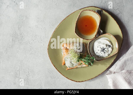 Flach mit Samosas in griescreme Teig mit Spinat und Paneer dekoriert mit gekeimten Samen von Luzerne und Sonnenblumenkerne auf Platte auf Grau gefüllt serviert. Stockfoto