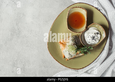 Blick von oben auf die samosas in griescreme Teig gefüllt mit Spinat und Paneer dekoriert mit gekeimten Samen von Luzerne und Sonnenblumenkerne auf Platte auf Grau serviert s Stockfoto