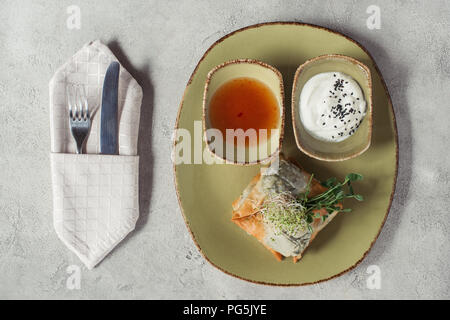 Blick von oben auf die samosas in griescreme Teig gefüllt mit Spinat und Paneer dekoriert mit gekeimten Samen von Luzerne und Sonnenblumenkerne auf Platte auf Grau serviert s Stockfoto