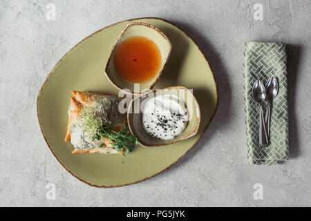 Flach mit Samosas in griescreme Teig mit Spinat und Paneer dekoriert mit gekeimten Samen von Luzerne und Sonnenblumenkerne auf Platte auf Grau gefüllt serviert. Stockfoto