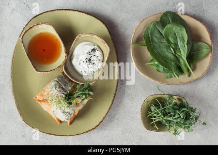 Die Zusammensetzung von Lebensmitteln mit Samosas in griescreme Teig gefüllt mit Spinat und Paneer dekoriert mit gekeimten Samen von Luzerne und Sonnenblumen auf dem Teller serviert. Stockfoto