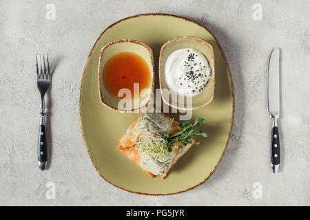 Flach mit Samosas in griescreme Teig mit Spinat und Paneer dekoriert mit gekeimten Samen von Luzerne und Sonnenblumenkerne auf Platte auf Grau gefüllt serviert. Stockfoto