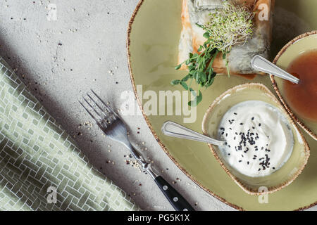 Blick von oben auf die samosas in griescreme Teig gefüllt mit Spinat und Paneer dekoriert mit gekeimten Samen von Luzerne und Sonnenblumenkerne auf Platte auf dem grauen t serviert. Stockfoto