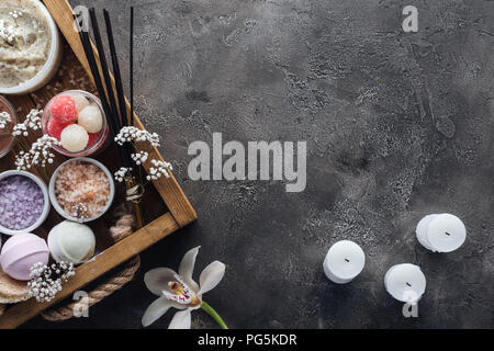 Blick von oben auf die Spa und Bad Accessoires im Holzkasten, Orchidee und Kerzen auf grauem Hintergrund Stockfoto