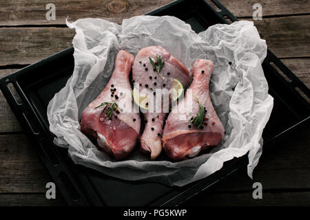 Unverarbeitete Türkei Beine mit Pfefferkörner, Rosmarin und Kalk auf Backpapier dish Stockfoto