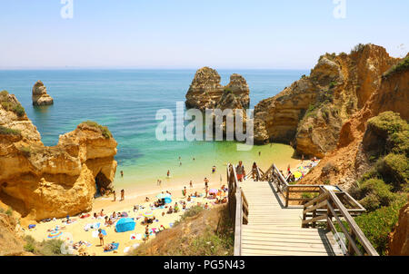 LAGOS, PORTUGAL - 23. JUNI 2018: die erstaunliche Landschaft mit Menschen klettern Holztreppe zu Praia Camilo Strand in der Nähe von Lagos, Algarve, Portugal Stockfoto