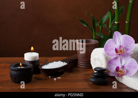 Spa Einstellung mit Meersalz, Kerzen, Handtücher, Steine und Orchideen. Stockfoto