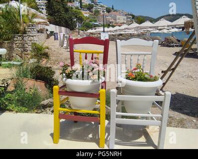 Griechenland, Insel Poros. Zwei alte Stühle, die auf skurrile Weise als Pflanzentopfhalter gestrichen und recycelt wurden Stockfoto