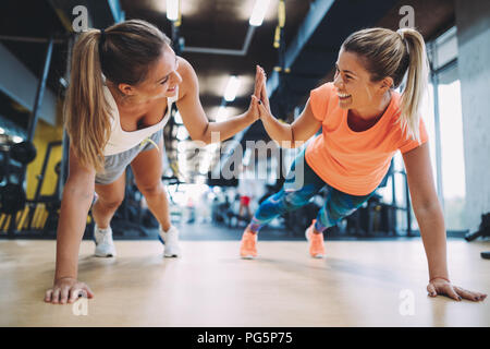 Zwei sportliche Mädchen, die Push-ups in der Turnhalle Stockfoto