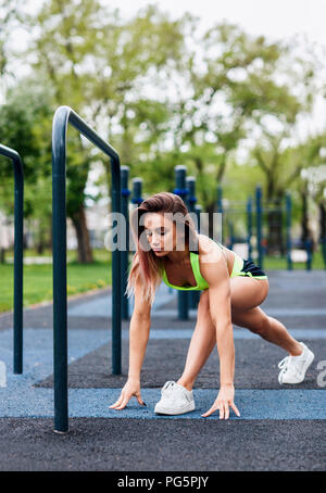 Junge Frau, die sich auf dem Sportplatz in den Park. Stockfoto