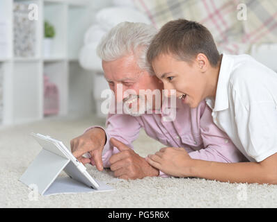 Großvater mit Enkel mit Laptop beim liegen auf dem Boden Stockfoto