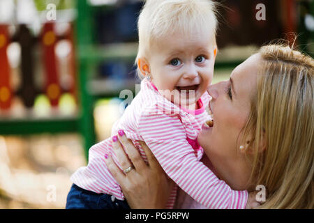 Kleines Mädchen und ihr schöne junge Mutter auf dem Spielplatz Stockfoto