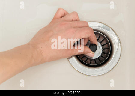 Frau Hand zieht close-Kappe von der Ablassöffnung der Spüle, Wasser ablassen Stockfoto