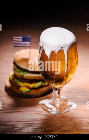 Leckere Burger mit einem Glas Bier auf hölzernen Tisch Stockfoto