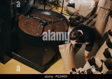 Mann Füllung Papiertüte mit frisch gerösteten Kaffeebohnen Stockfoto