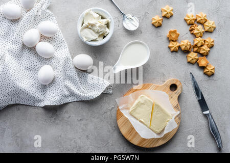 Flach mit geschnittenen Butter, Cookies und rohem Huhn eier Zutaten für eine Torte auf graue Oberfläche Stockfoto