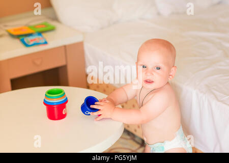 Süße kleine Baby Junge spielt mit Stapeln cups im Zimmer Stockfoto