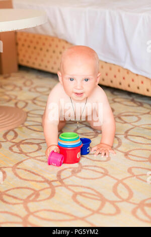 Süße kleine Baby Junge spielt mit Stapeln cups im Zimmer Stockfoto