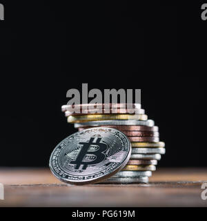 Nahaufnahme Blick auf bitcoin lehnte sich auf Stapel von verschiedenen Bitcoins auf schwarzem Hintergrund Stockfoto