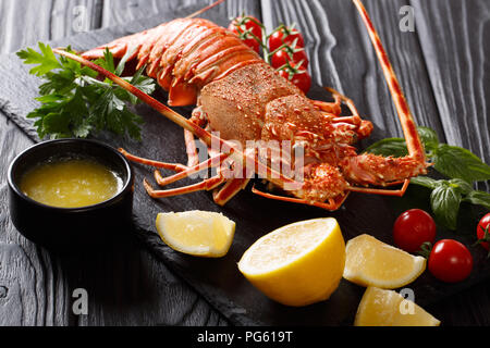 Gekochte rote oder Stacheligen Rock Lobster mit Gemüse und zerlassener Butter close-up auf einem schwarzen Hintergrund. Horizontale Stockfoto