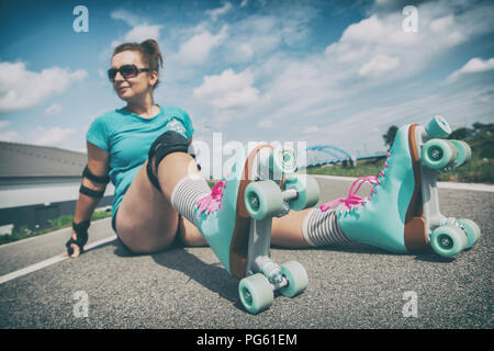 Frau, die in einem Jahrgang Rollschuhe, retro Quad skates Sitzen im Freien. Stockfoto