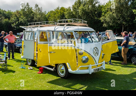 Gelbe und weiße split screen VW Wohnmobil auf einem Oldtimertreffen in Wales. Stockfoto