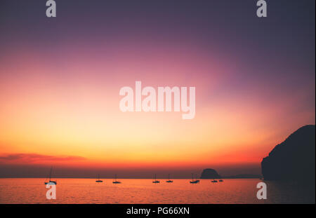 Schönen und ruhigen Blick auf den Sonnenuntergang über der Lagune/Bay mit ein paar Yachten und Inseln in der Ferne; Klein, perfekte Inseln im südlichen Thailand Stockfoto