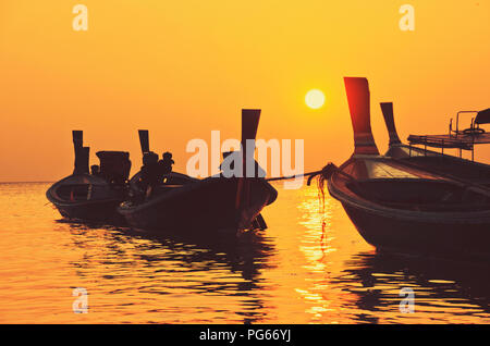 Sechs (6) Thai (longtail) Holz- Boote schwimmend und Glitzernd in der Lagune bei Golden Sunset, Koh Lanta Island, Thailand Stockfoto