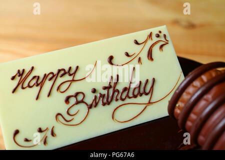 Nahaufnahme von Happy Birthday auf der Karte aus weißer Schokolade aufgefüllt Geschrieben am Schokolade Kuchen Begrüßung Stockfoto