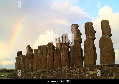 Tolle Aussicht auf der Rückseite der 15 riesigen Moai Statuen der Ahu Tongariki mit dem Regenbogen auf bewölkten Himmel im Hintergrund, archäologische Stätte in Osterinsel Stockfoto