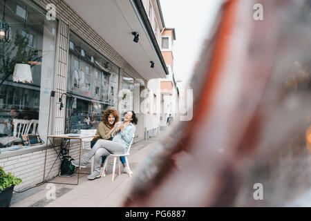 Zwei lachen Freunde sitzen vor Coworking Space Stockfoto