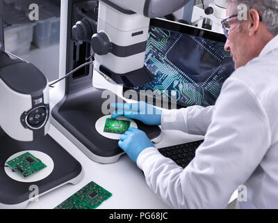 Techniker mit Hilfe eines 3-D Stereo Mikroskop für die Qualitätskontrolle in der Herstellung von Platinen für die Elektronikindustrie Stockfoto