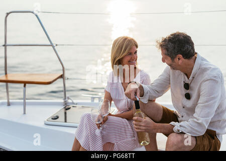 Reifes Paar trinken Wein bei Sonnenuntergang auf dem Segelboot Stockfoto