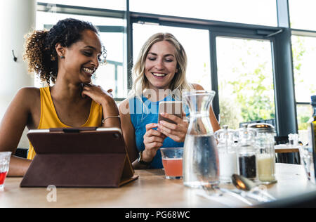 Beste Freunde treffen im Cafe, im Gespräch und Austausch von Nachrichten, mit digitalen Tablet Stockfoto
