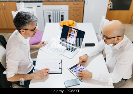 Zwei Kollegen arbeiten auf Fotografien am Tisch zu Hause Stockfoto