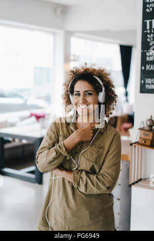 Junge Frau mit Kopfhörer, arbeiten in Coworking Space Stockfoto